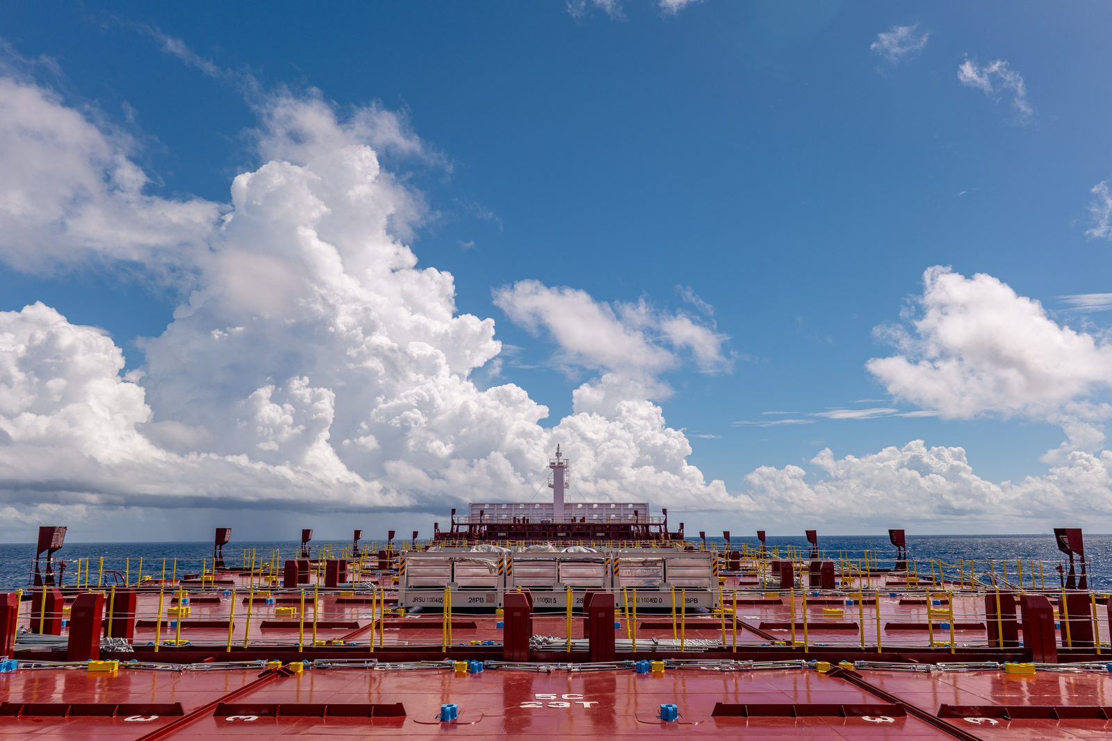 Container ship deck beneath cumulus clouds