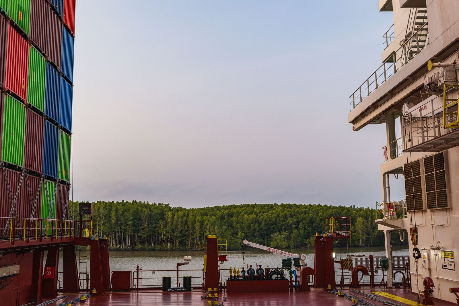 Mangrove forest along a river seen between the ship's structures