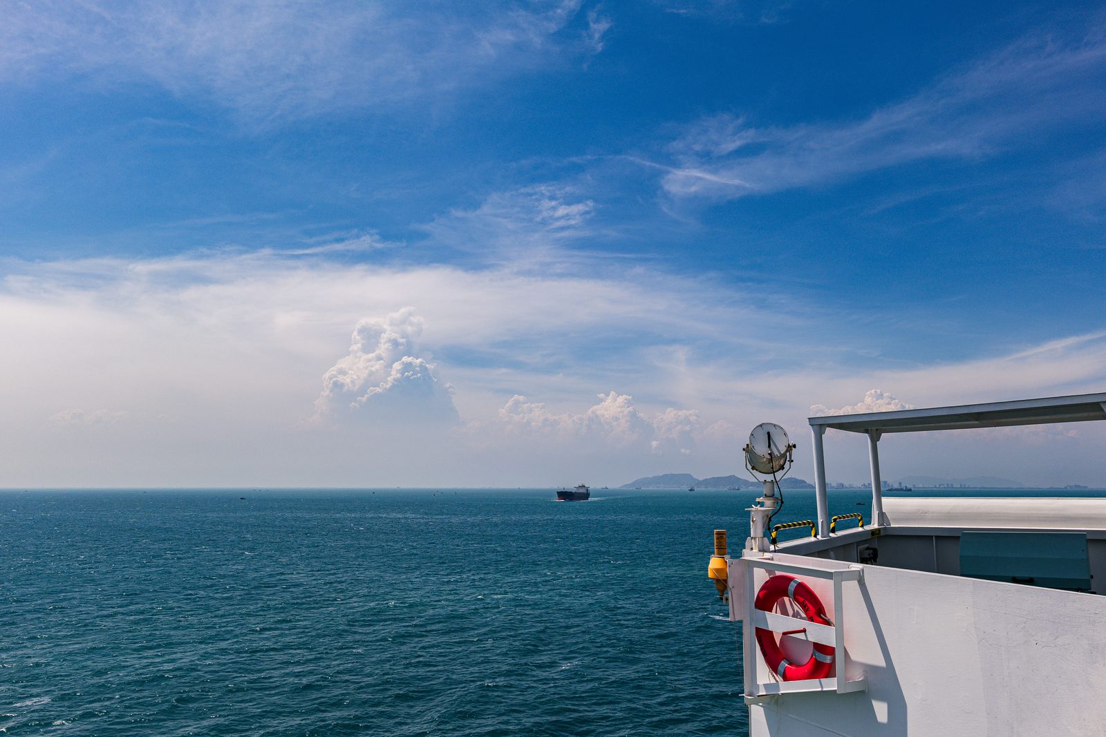 A distant ship as a small point on the sea, beside the vessel's own white superstructure