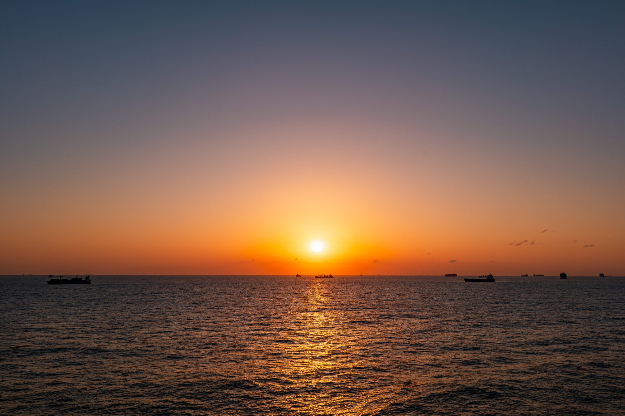 Ships at anchor silhouetted against sunset, Shanghai Anchorage